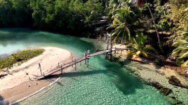Experience the serene charm of Koh Kood, Thailand, where crystal-clear waters meet soft sands. A picturesque wooden bridge leads to adventure amid lush palm trees and stunning coastal views.