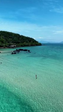 Enjoy the stunning beauty of Koh Kham Island with its clear turquoise waters and soft sandy beach. Visitors can swim, relax, a couple of caucasian men and Asian women on vacation