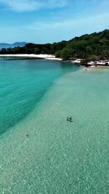 Expansive views of Koh Kham Island reveal soft sandy beaches and vibrant blue waters. Visitors enjoy the serene landscape, perfect for relaxation and exploration under the sunny skies of Thailand.