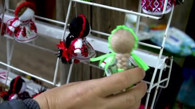 Bir el, Ukrayna süslemelerinden yapılmış el yapımı küçük bir bez bebeği tutuyor. Bezden yapılmış oyuncak bebek, Ukrayna süslemeleri ile parlak renkli bir elbise giydi..