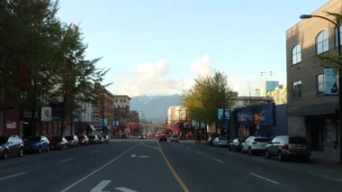 Vancouver 'ın ana caddesinde gün batımında bir araba geçerken.