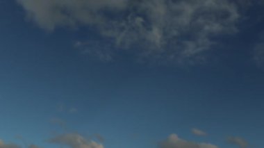 Mavi gökyüzünde sağdan sola hareket eden yumuşak stratus bulutları. 4K zaman dilimi