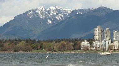 Karlı zirvesi olan dağ Vancouver 'da dalgalar üzerinde demirli yat sallanıyor.