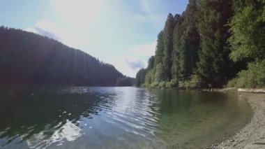 Lake timelapse with clouds and forest reflection with a sun flare