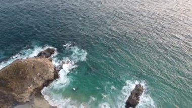 Kristal gibi berrak suyun üzerinde uçarken kayalık bir kıyıya çarpar..