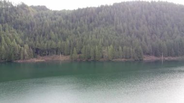 Bir cennette süzülen: bulutların altındaki sakin göl ve ormanın havadan görünüşü