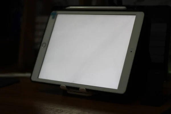 テーブルの上に白い画面のある空のタブレットの写真 — ストック写真