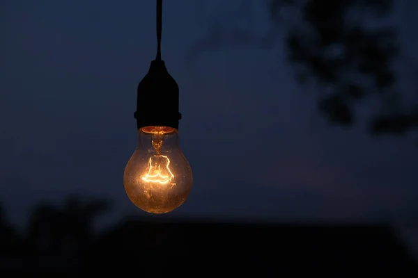 Stock image photo of yellow light bulb glowing at night