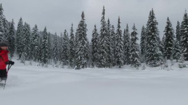 Kış yürüyüşünde olan üç adam kar ayakkabılarıyla kar altında yürüyorlar. 