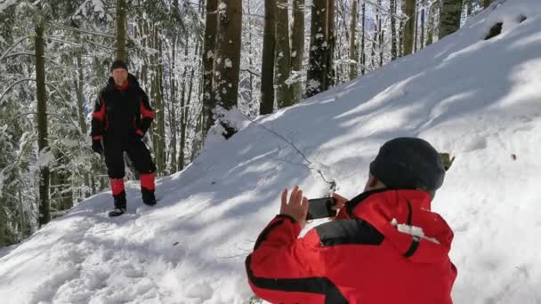 徒步旅行者在冰雪覆盖的森林里拍摄冬季远足的照片 — 图库视频影像