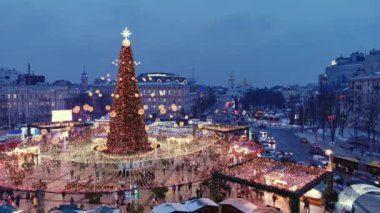 İnsanlar kasaba meydanındaki Noel ağacının yanındaki Noel fuarında yürüyorlar. Noel tatili