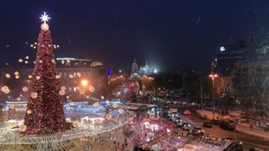 Ukrayna, Kiev 'deki Sofievskaya Meydanı' nda Noel festivali ve Noel ağacı. St. Michael Katedrali uzaktan aydınlatılır. Kaygan yolda arabalar yavaşça geçer.. 
