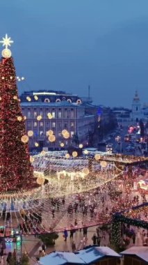 İnsanlar Noel ağacının yakınındaki Noel panayırında dolaşıyorlar. Dikey Video