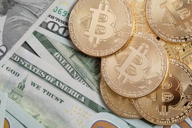 Gold-colored coins representing virtual cryptocurrency lie on the background of American dollars. The concept of converting virtual assets into real ones.