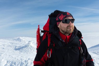 Man in winter hike. He has a backpack and snowshoes. Portrait