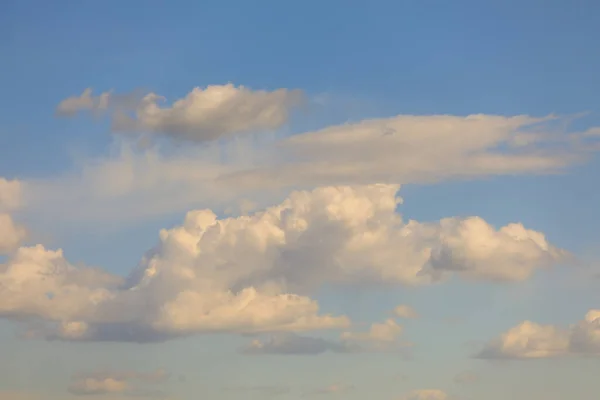 Fluffy clouds illuminated by the yellow light of the setting sun