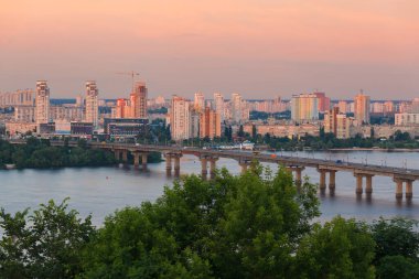 Kyiv, Ukrayna - 2 Haziran 2014: Bu fotoğraf Paton Köprüsü 'nü günbatımında Dinyeper Nehri üzerinde, arka planda yeni binalarla gösteriyor. Günbatımının ve modern mimarinin zıt renkleri şehrin görüntüsünü büyülüyor. 