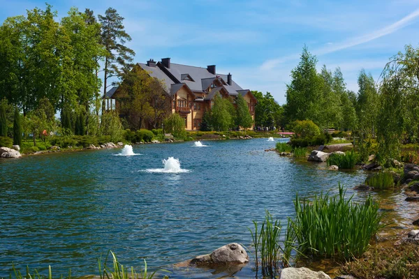 stock image Novye Petrovtsy, Ukraine - May 7, 2014: Landscape of Yanukovych's residence on a sunny summer day. In the background, a house is visible, surrounded by lush greenery, while in the foreground, a picturesque body of water adds beauty and tranquility to