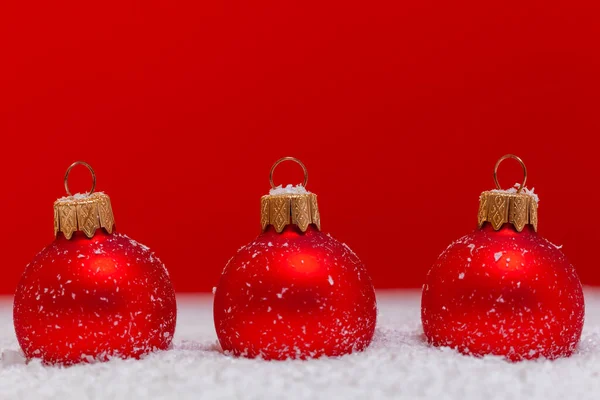 Kıpkırmızı Arkaplan Üzerine Parlayan Karlı Süsler: Neşeli Bir Noel Sahnesi