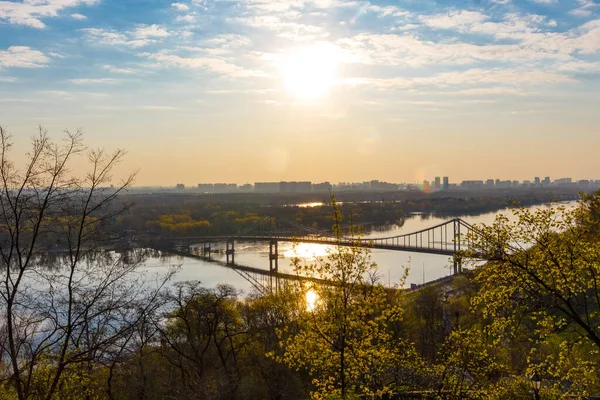 Güneş Kiev 'in sol kıyısından doğuyor. Şehir manzarası. Dinyeper üzerindeki yaya köprüsü. 