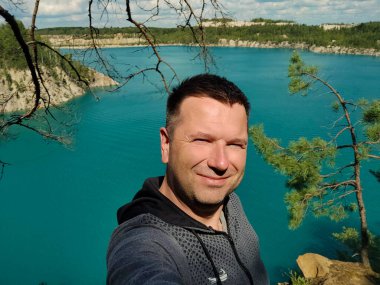 Bir adam, bir yaz öğleden sonrasında güzel bir manzaranın karşısında fotoğraf çekilir.