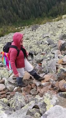 Yürüyüş yaparken kayalık bir yola tırmanan sırıklı bir kadın.