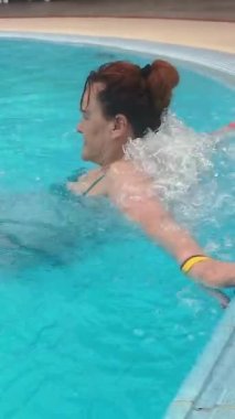 Kadın açık havuzda yüzmekten ve su altında masaj yaptırmaktan hoşlanıyor.