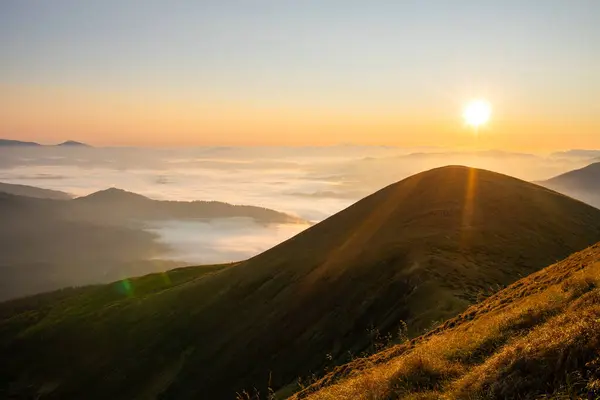 Sabahın erken saatlerinde dağlarda. Güneş bulutların üzerinden doğar. 