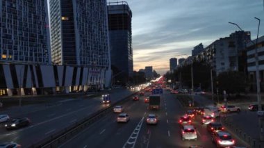 Üç şeritli bir yolda araç trafiği. Akşam vakti. Arabalar yolu aydınlatmak için farlar kullanıyor.. 