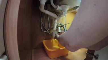 Tesisat bakımı. Bir adam servis sonrası mutfak lavabosunun altına U şeklinde bir boru yerleştiriyor..