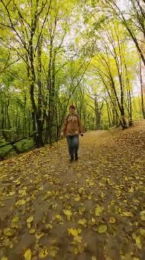 Sonbahar ormanında yürüyüş yapan bir kadın. Dikey Video
