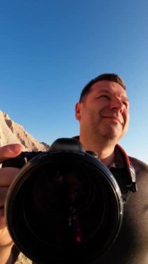 Fotoğrafçı etrafına bakar ve çevredeki manzaranın birkaç fotoğrafını çeker. Bakış açısı. Dikey Video