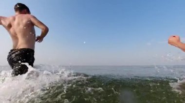 Bir adam ve bir kadın okyanusa koşar, arkalarından su sıçratırlar. Sahne yavaş çekimde, tatilde ya da dinlenirken eğlenceli bir su aktivitesi izlenimi veriyor..