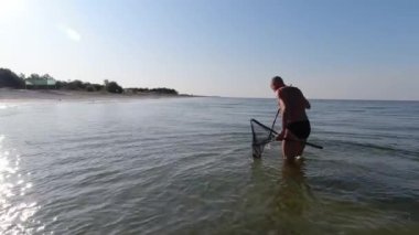 Bir adam ev yapımı mızrak ve ağ kullanarak Karadeniz 'i sığ sularda avlıyor..