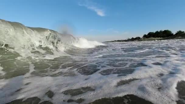 Une vague de mer s'écrase contre le rivage, recouvrant le caméraman. Mouvement lent