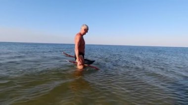 Bir adam ev yapımı mızrak ve ağ kullanarak Karadeniz 'i sığ sularda avlıyor..
