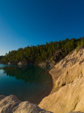 Güzel bir göl ve sabah güneşiyle ışıldayan küçük bir plaj. Peyzaj