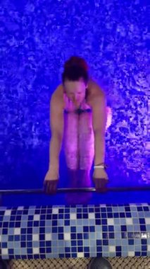 Mavi bir su havuzu ve içinde yüzen bir kadın.. 