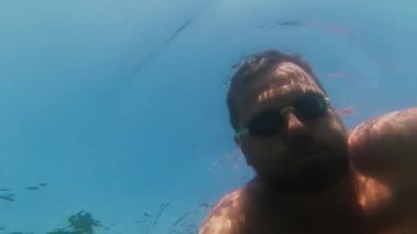 Yüzme gözlüklü bir adam suya dalıp yüzer.