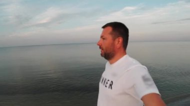 Bir adam deniz kıyısında koşuyor. Spor yapıyor.