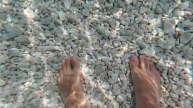 Güneşli bir yaz gününde deniz suyunda insan ayağı