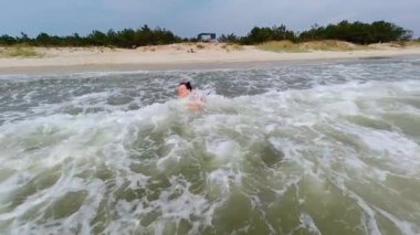 Bir kadın yaz tatilinde sahilde deniz dalgalarının tadını çıkarır. Yavaş Hareket