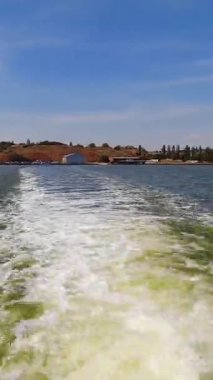 Kıyıdan uzaklaşan bir tekne yolu. Hiperlapse. Dikey Video
