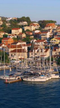 Akşam şehri manzarası. Marina ve demirli yatlar akşam güneşiyle aydınlanır. Trogir, Hırvatistan. Dikey Video
