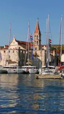 Güneşli bir yaz gününde Hırvat adalarından birinin limanında demirli yatlar ve botlar. Dikey Video