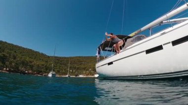 Güneşli bir günde Yat güvertesinden suya dalan bir kadın. Su yüzeyinin üstünde ve altında görünün. Yavaş Hareket