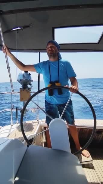 双眼鏡を持った男がヘルメットを握り ヨットを操る 垂直ビデオ バーティカルビデオ — ストック動画