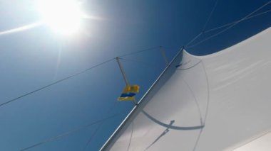 Mavi gökyüzü ve güneşin arka planında yelken açmak. Aşağıdan yukarıya bak