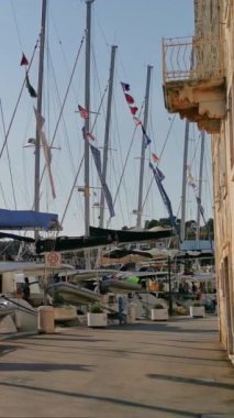 Güneşli bir yaz gününde marinada bir sürü yat ve tekne var. Hırvatistan 'daki adalardan birinin limanı. Dikey Video