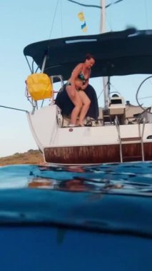 A woman is enjoying her summer vacation on a yacht. Over and Under. Vertical Video